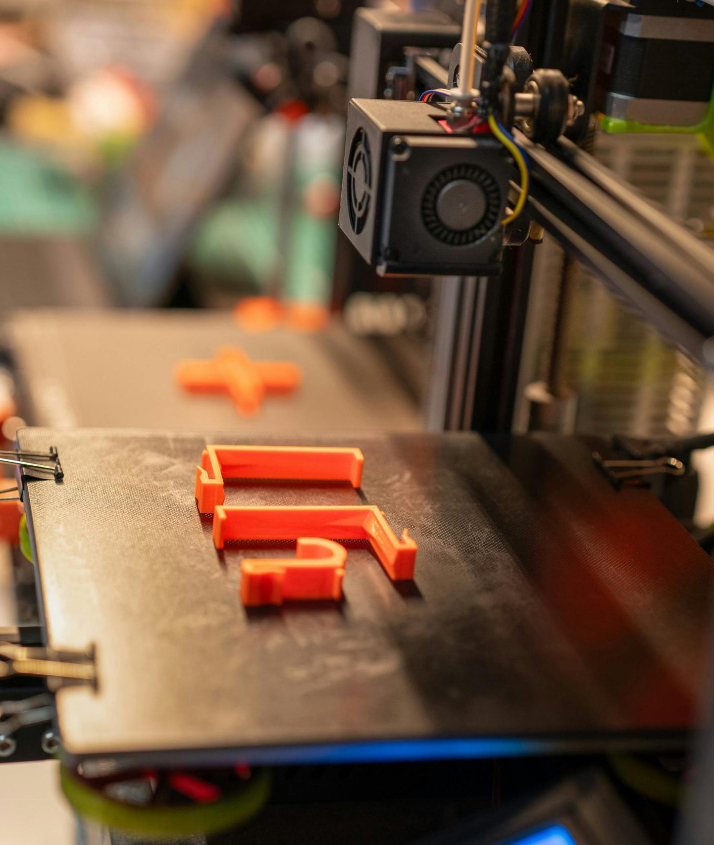Detailed view of a 3D printer creating an orange plastic part showcasing advanced technology.