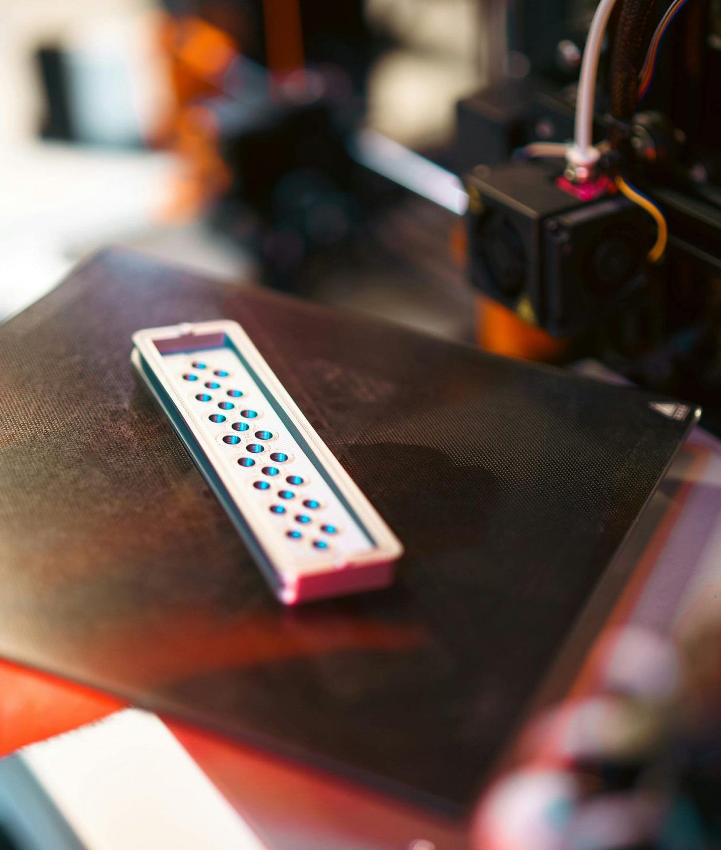 Close-up of a 3D printed part on an industrial printer in a workshop setting.