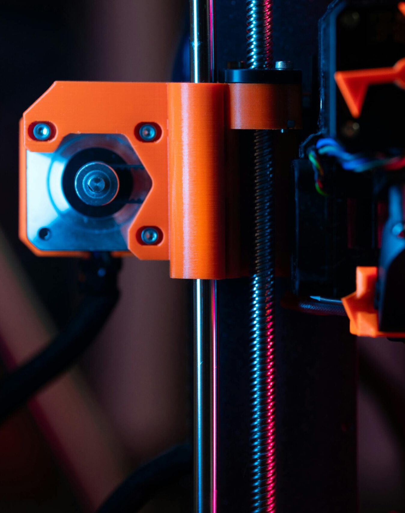 A detailed close-up of a 3D printer showcasing its extruder and components under vibrant lighting.